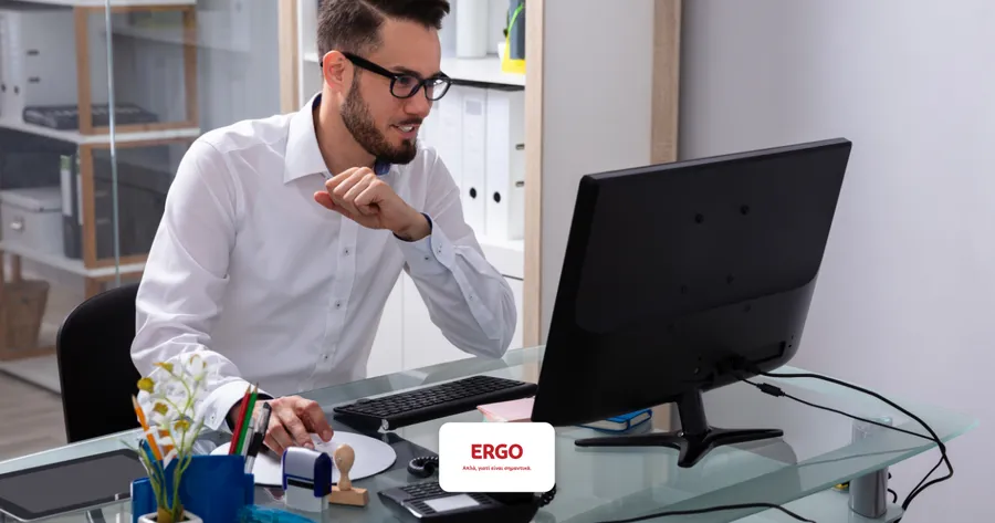 Ευρωπαίος με γυαλιά και λευκό πουκάμισο συγκεντρωμένος σε desktop οθόνη — ERGO Cyber Insurance